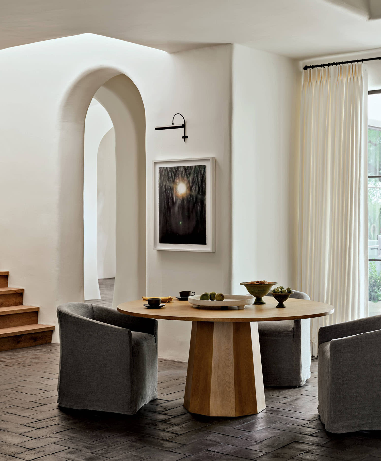 A pedestal table and chairs in a breakfast nook with terra-cotta tile and artwork on a nearby wall.