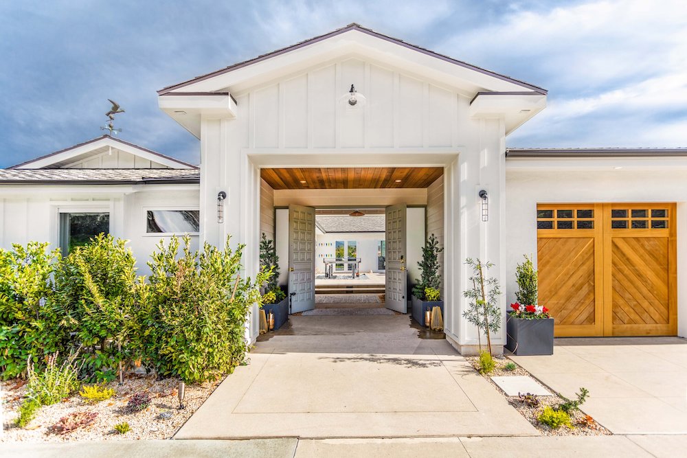 A contemporary white home with clean lines, wood garage doors and large entry way by Kabbany Architecture in Southern California.