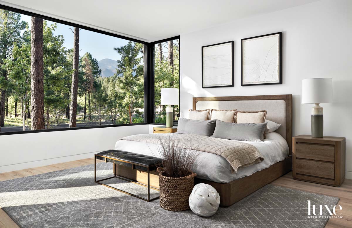 A white zen bedroom with wood furniture and views of the woods.