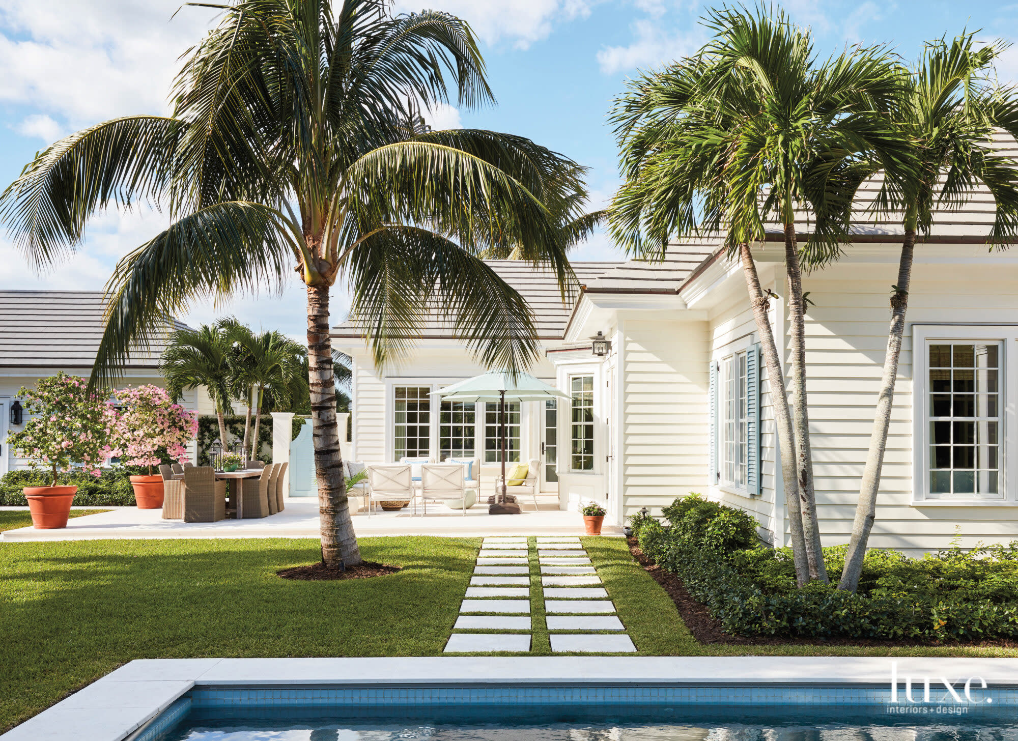 Back terrace with white armchairs with blue and white pillows.