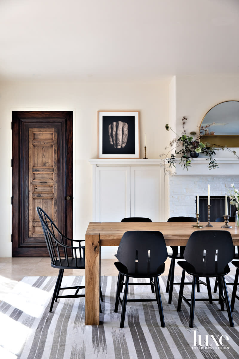 The dining room has a light colored table surrounded by dark chairs.