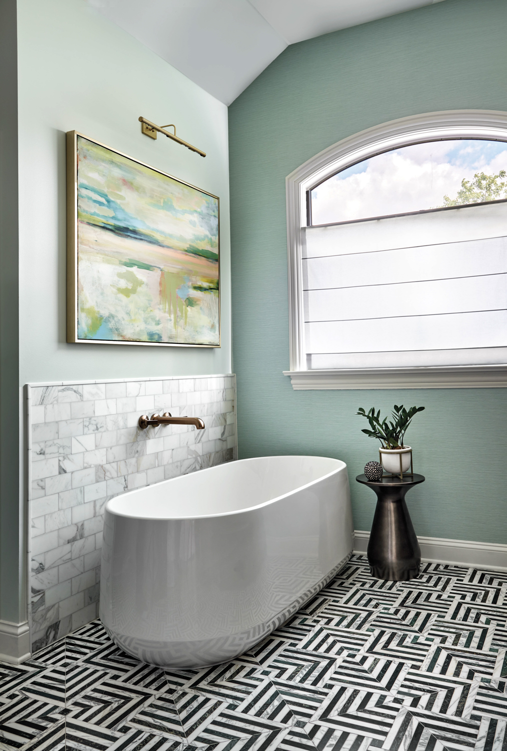 freestanding bathtub in a sea green bathroom with black-and-white geometric tile