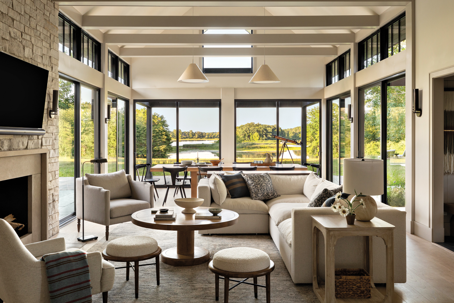 living room with white seating, a limestone fireplace and floor-to-ceiling windows