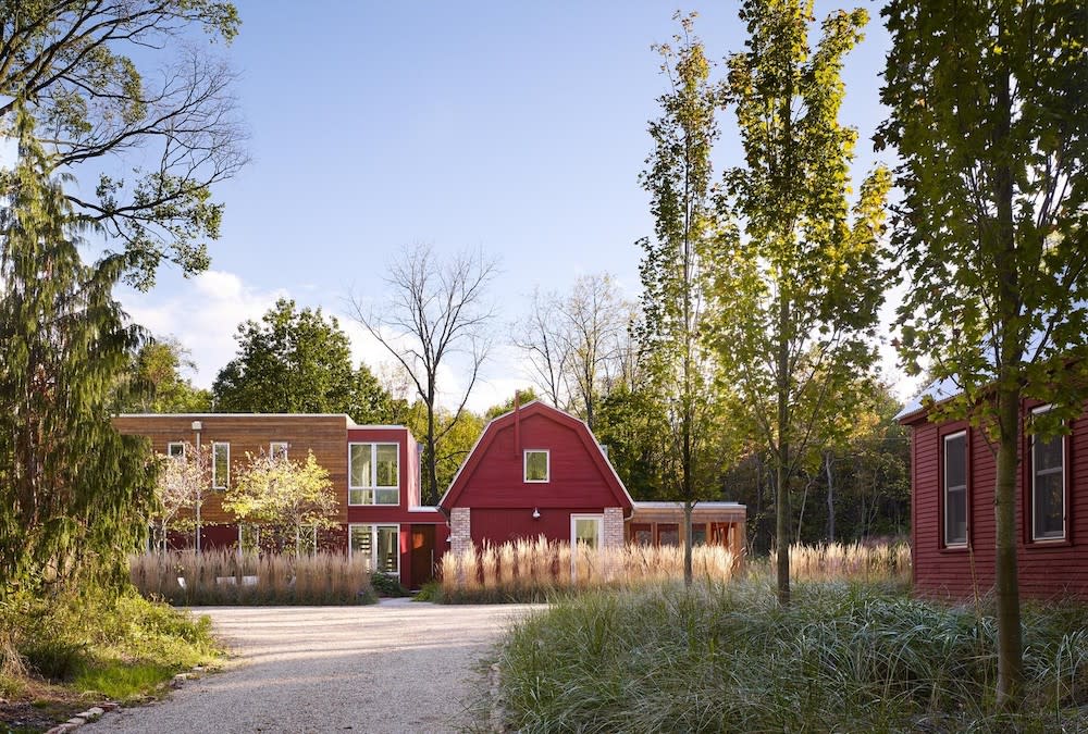 Exterior of home red barn with wood, green landscaping and rock driveway