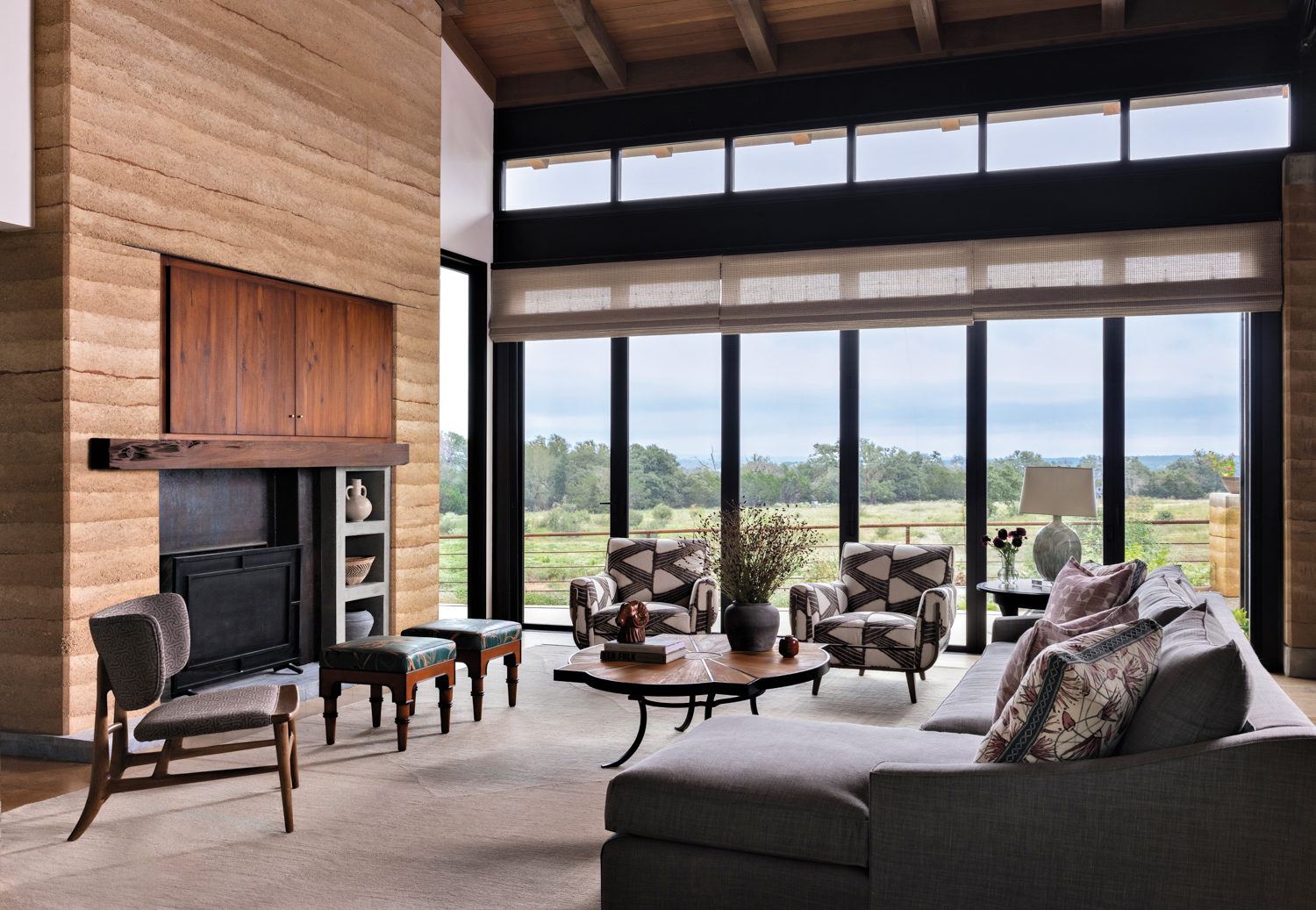 living room with a fireplace surrounded by rammed earth