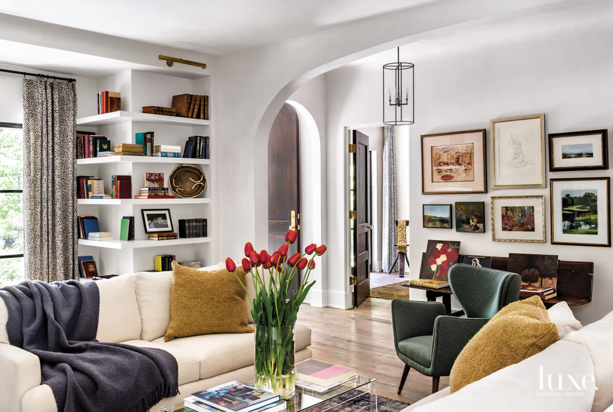 bright living room with wall art, built-in shelves and a curved doorway