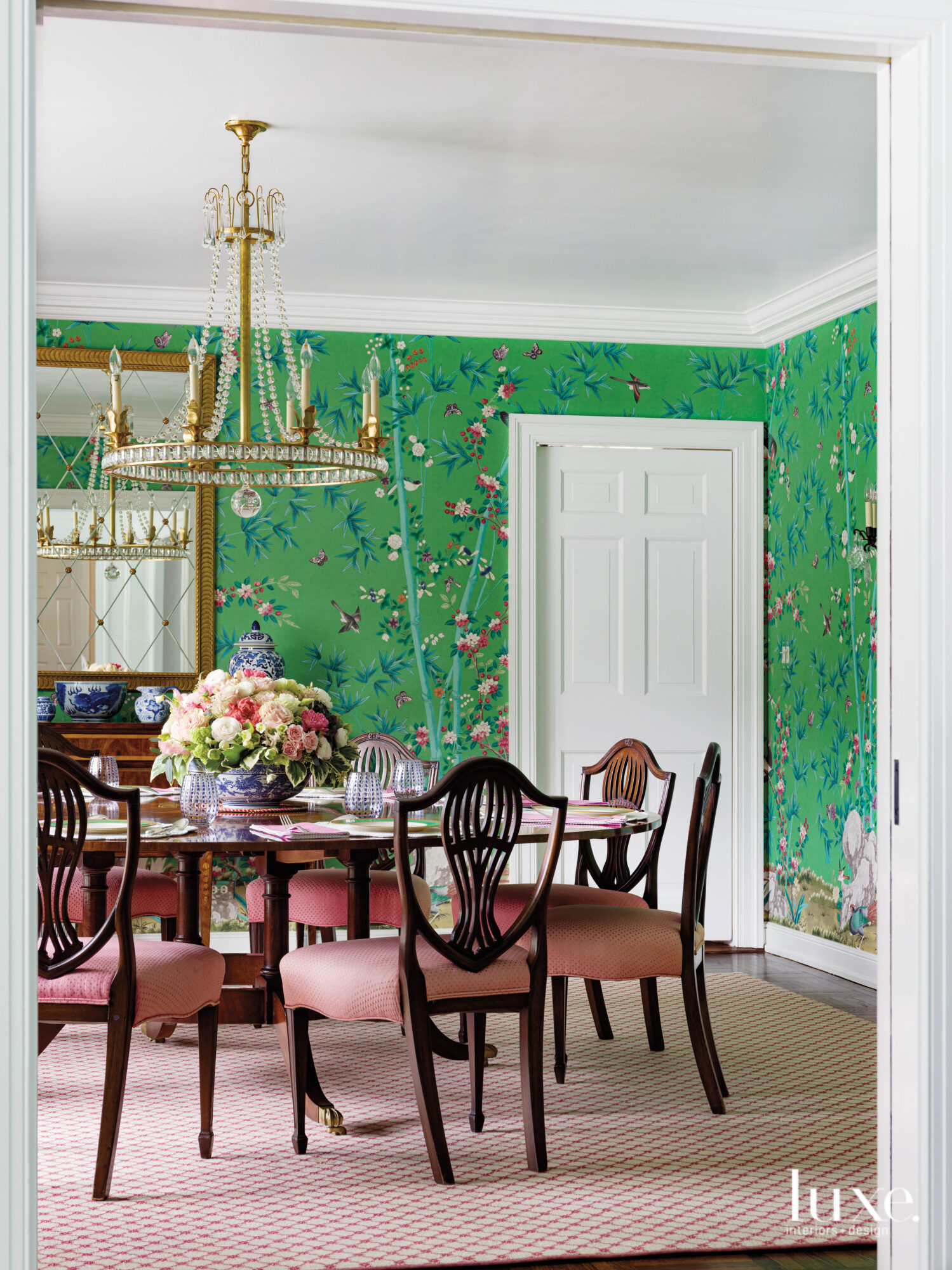 The dining room has green floral wallpaper with a traditional dining table and pink upholstered chairs.