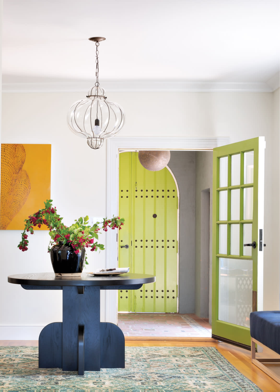 An entry with a green door and black round table.