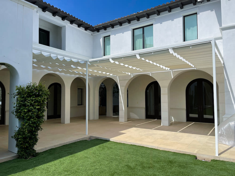 exterior of white home with curved doors and custom wire awnings