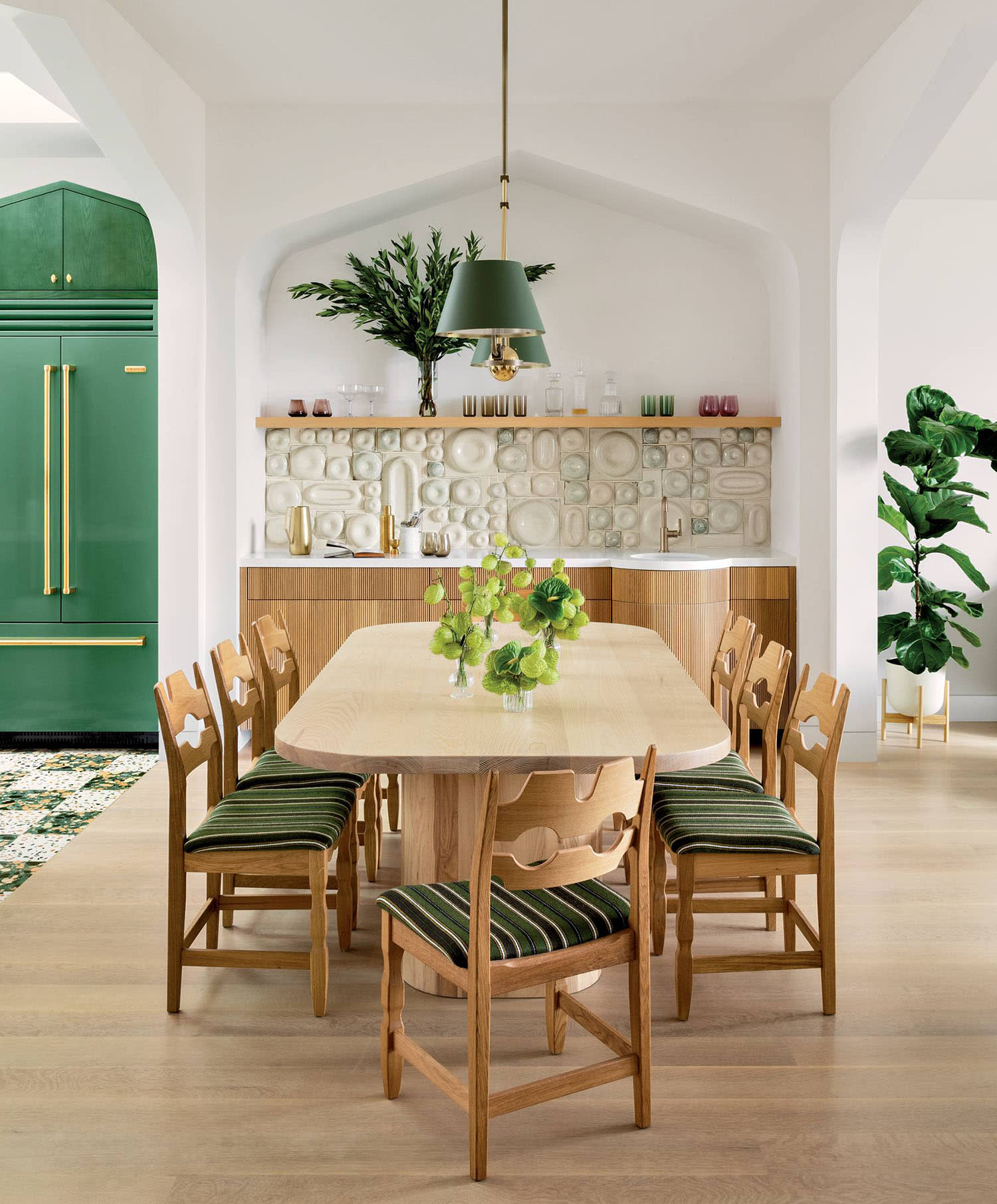 vintage chairs surround a dining table in a green accented modern organic-style room