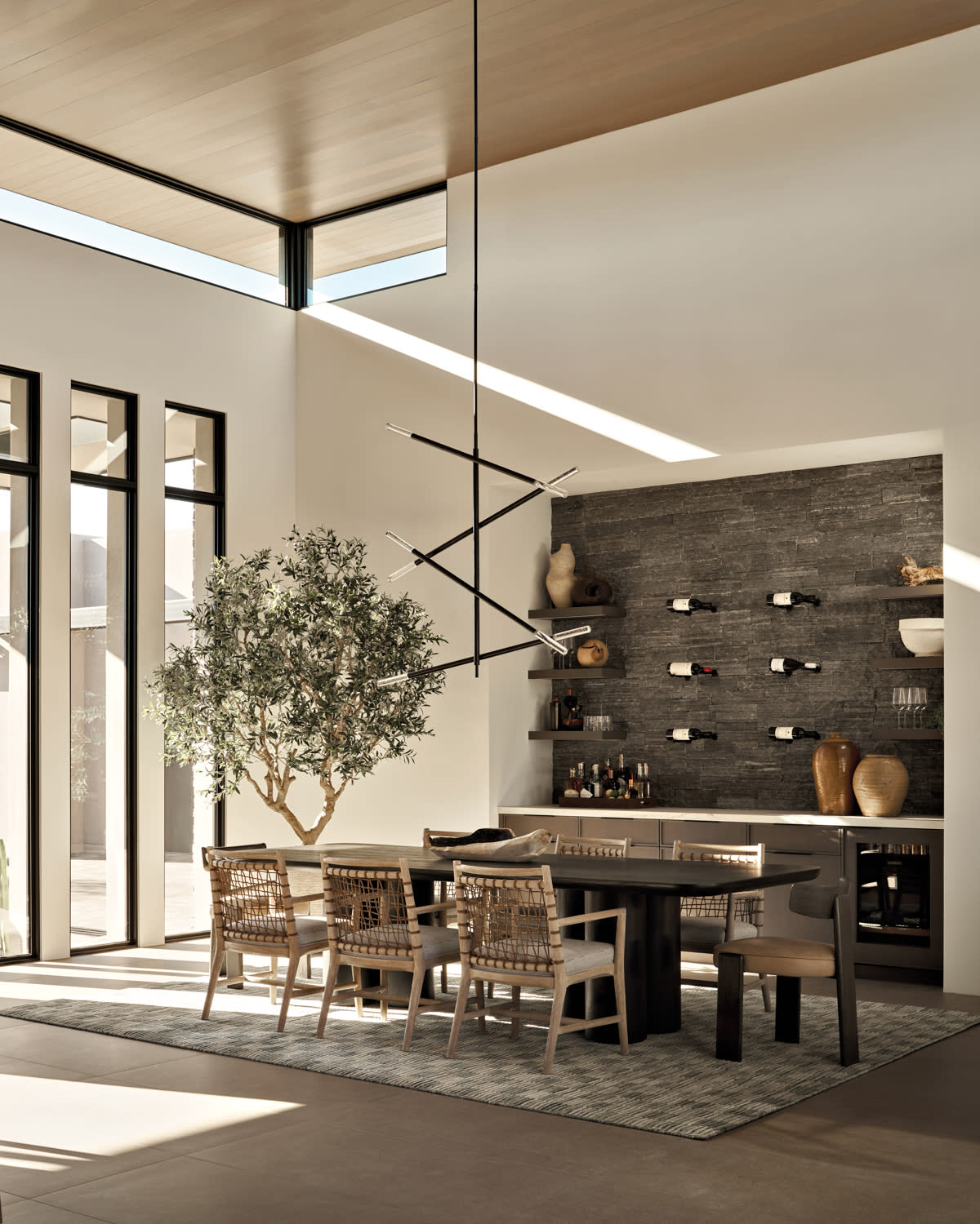 sleek, contemporary dining room with woven chairs and a sculptural pendant over the dining table