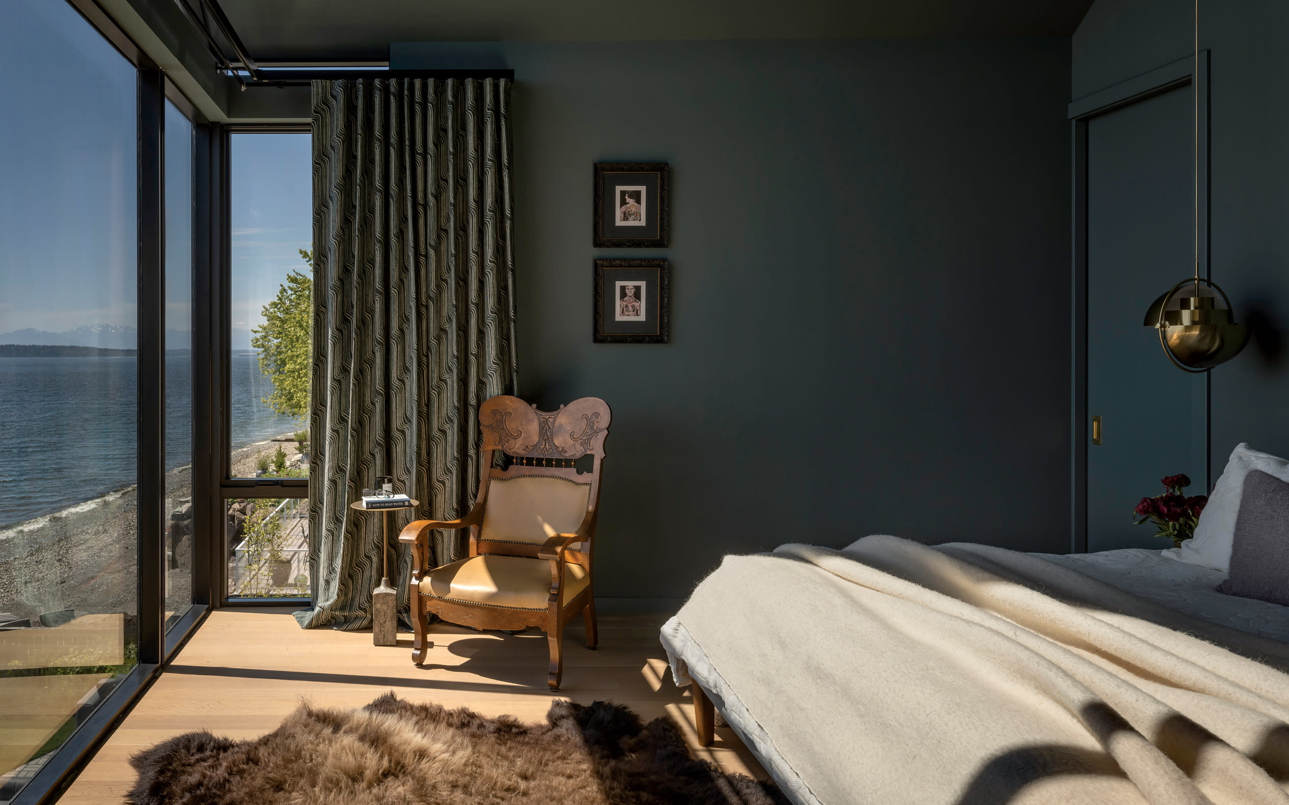 blue-green bedroom with a vintage rocking chair and views of a waterway out a large window