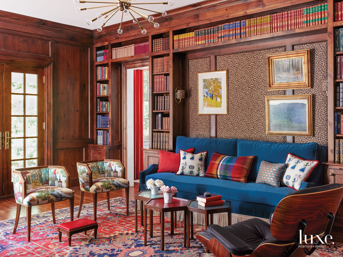 library with leopard print wallpaper, blue sectional and geometric tables