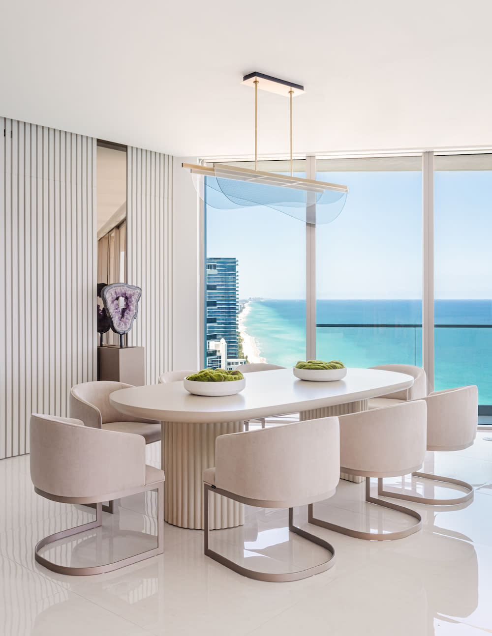 A beautifully arranged dining room with a breathtaking ocean view visible through large, inviting windows.