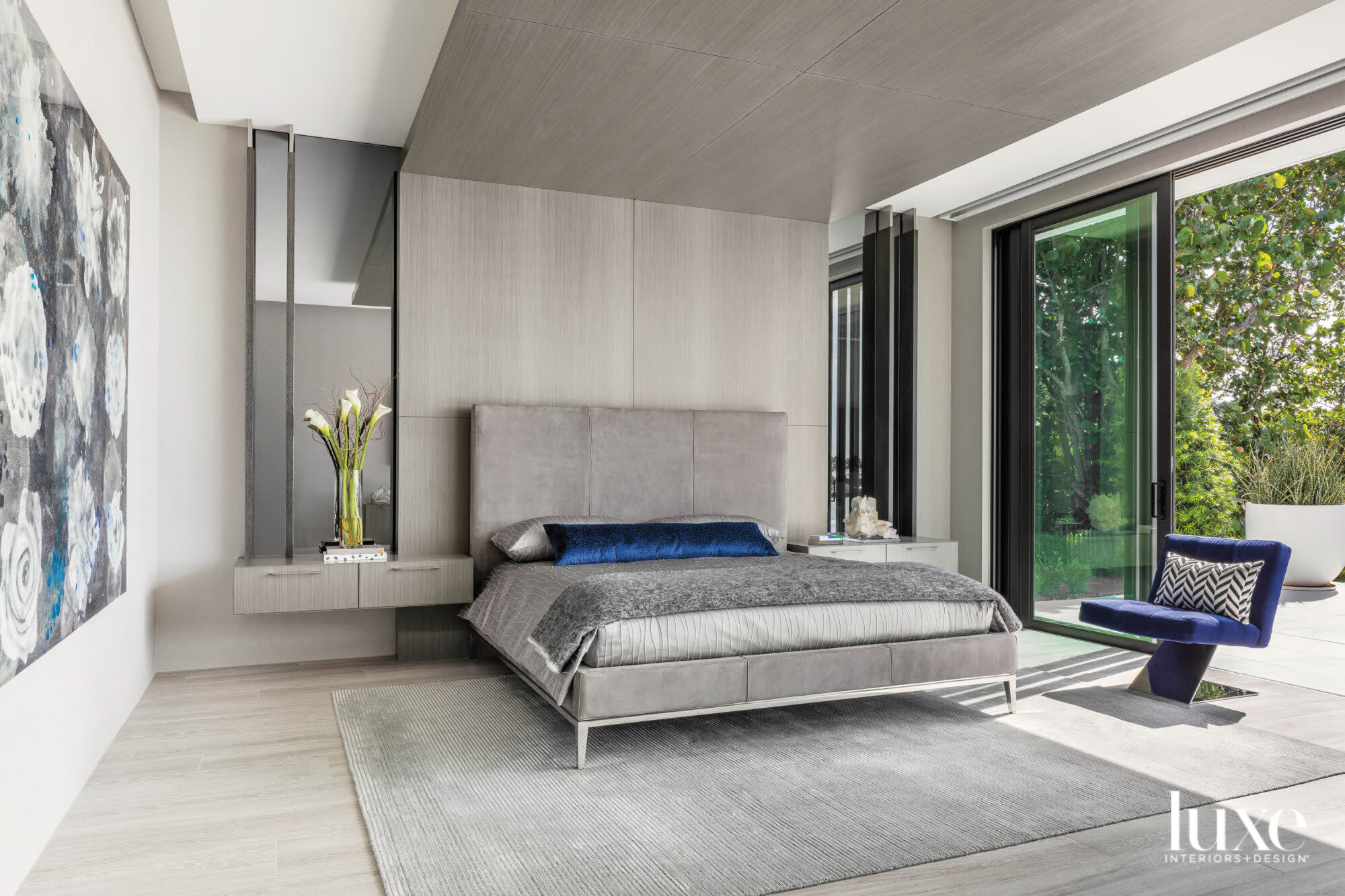 contemporary bedroom with headboard wall and ceiling, gray bed and blue armchair