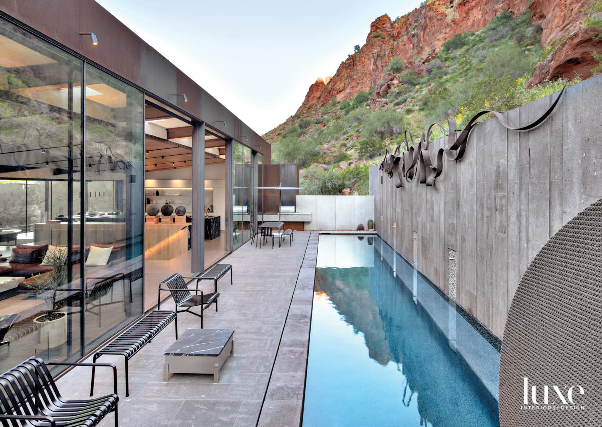 A back patio with a long slender pool. You can see the mountains behind it.