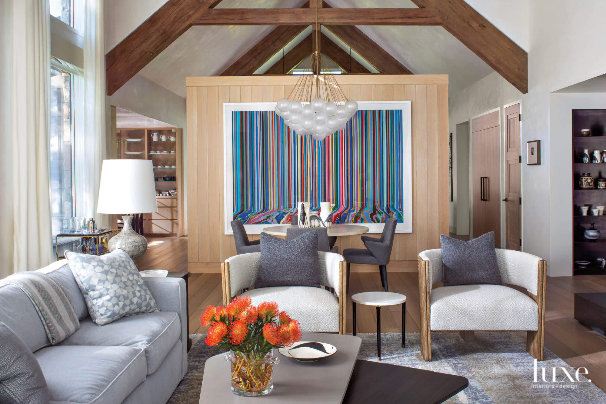 From the living room, you can look into the dining room which is decorated with a rainbow-stripe artwork.