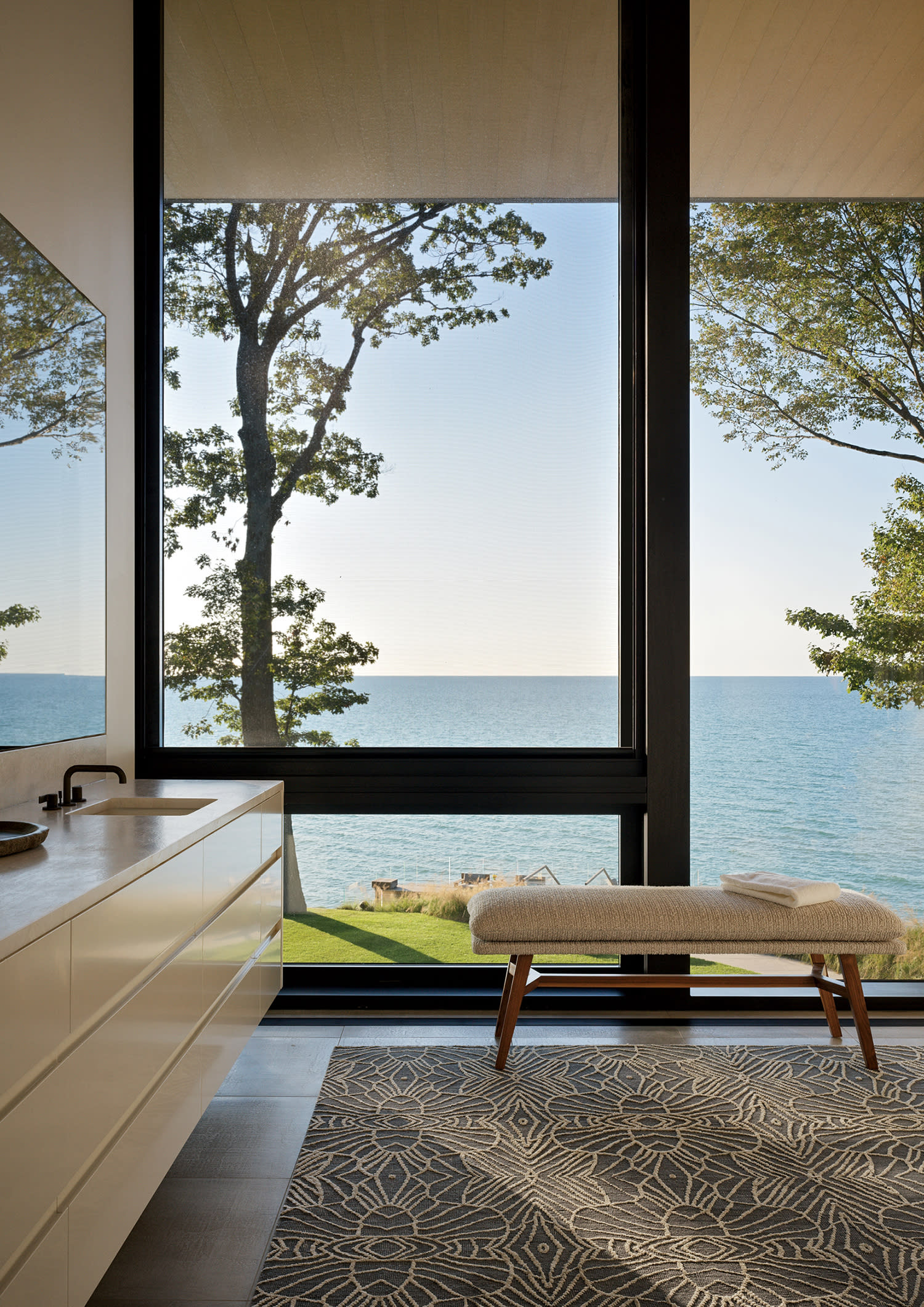 modern bathroom with a bench in front of a large window overlooking a lake
