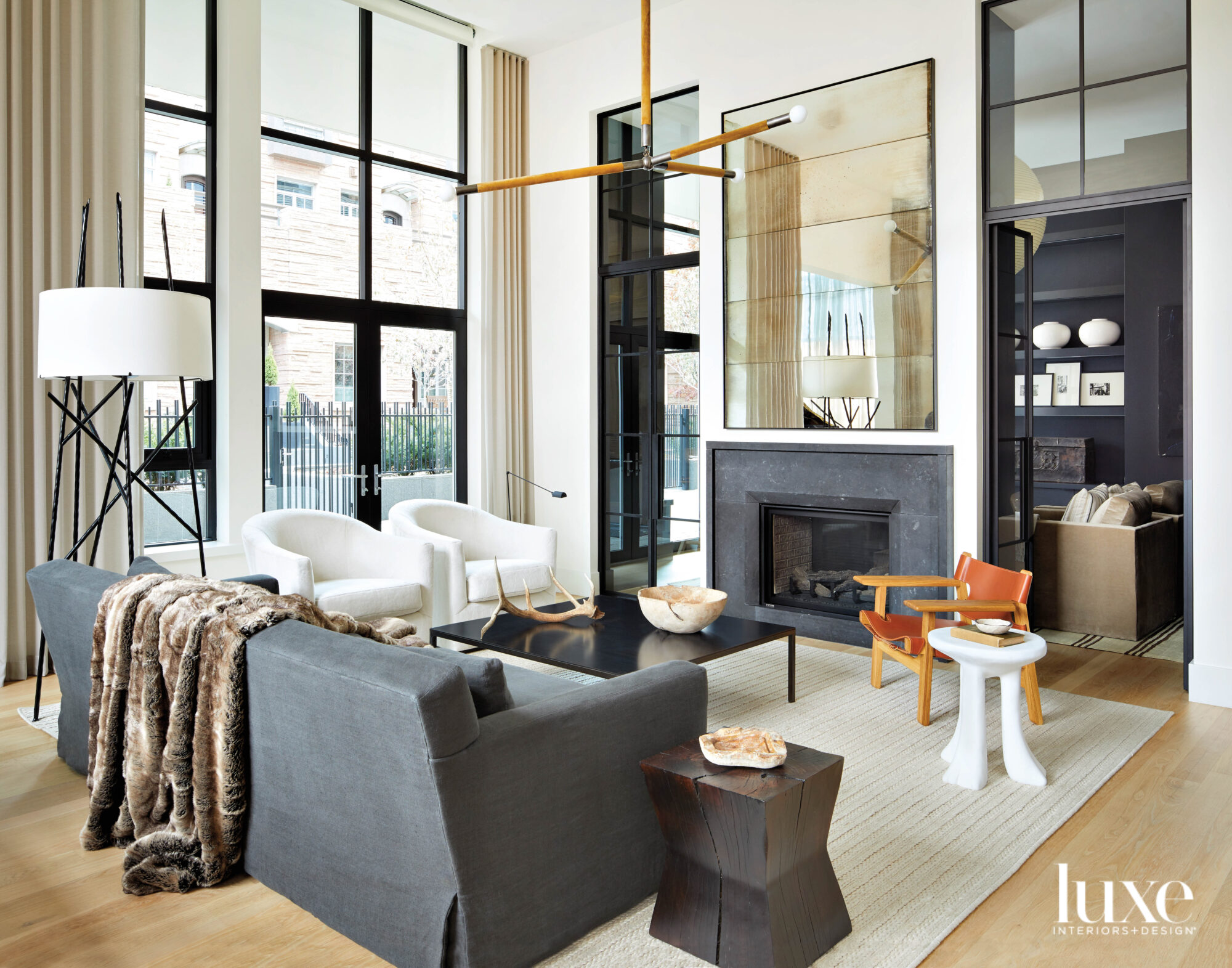 A living room is arranged around a fireplace composed of black stone and mirrored panels.