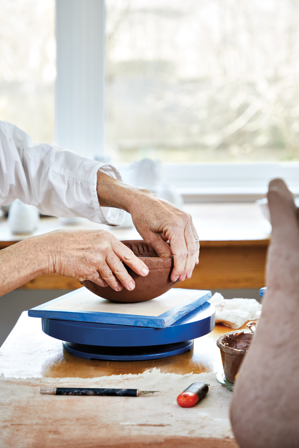 hands forming a clay bowl