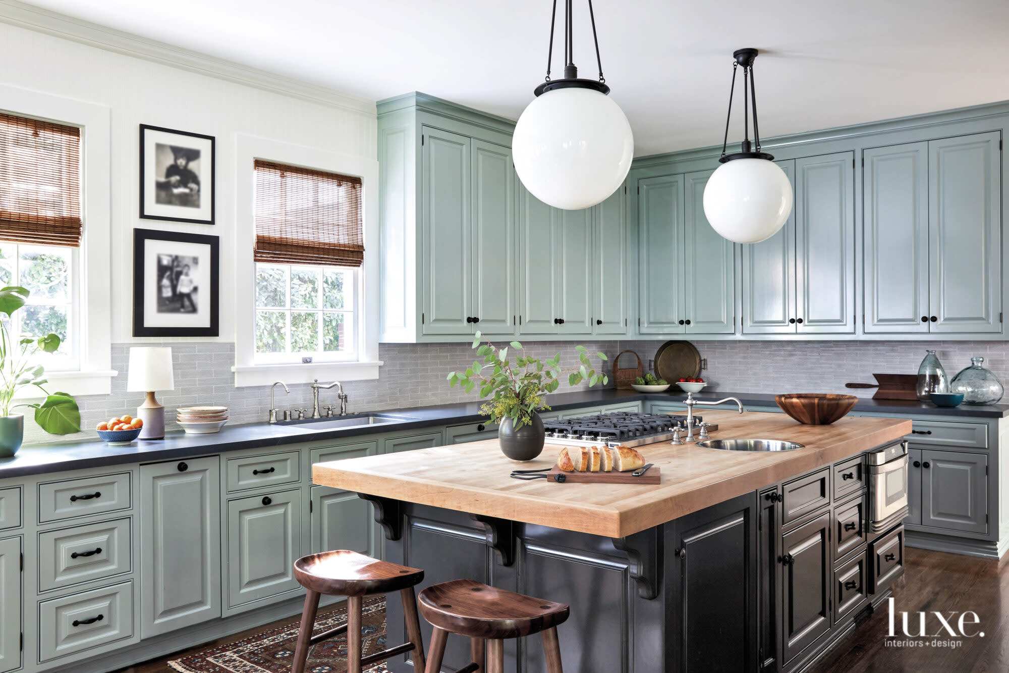 Kitchen with pale green painted cabinets and a wood counter island with black cabinets.