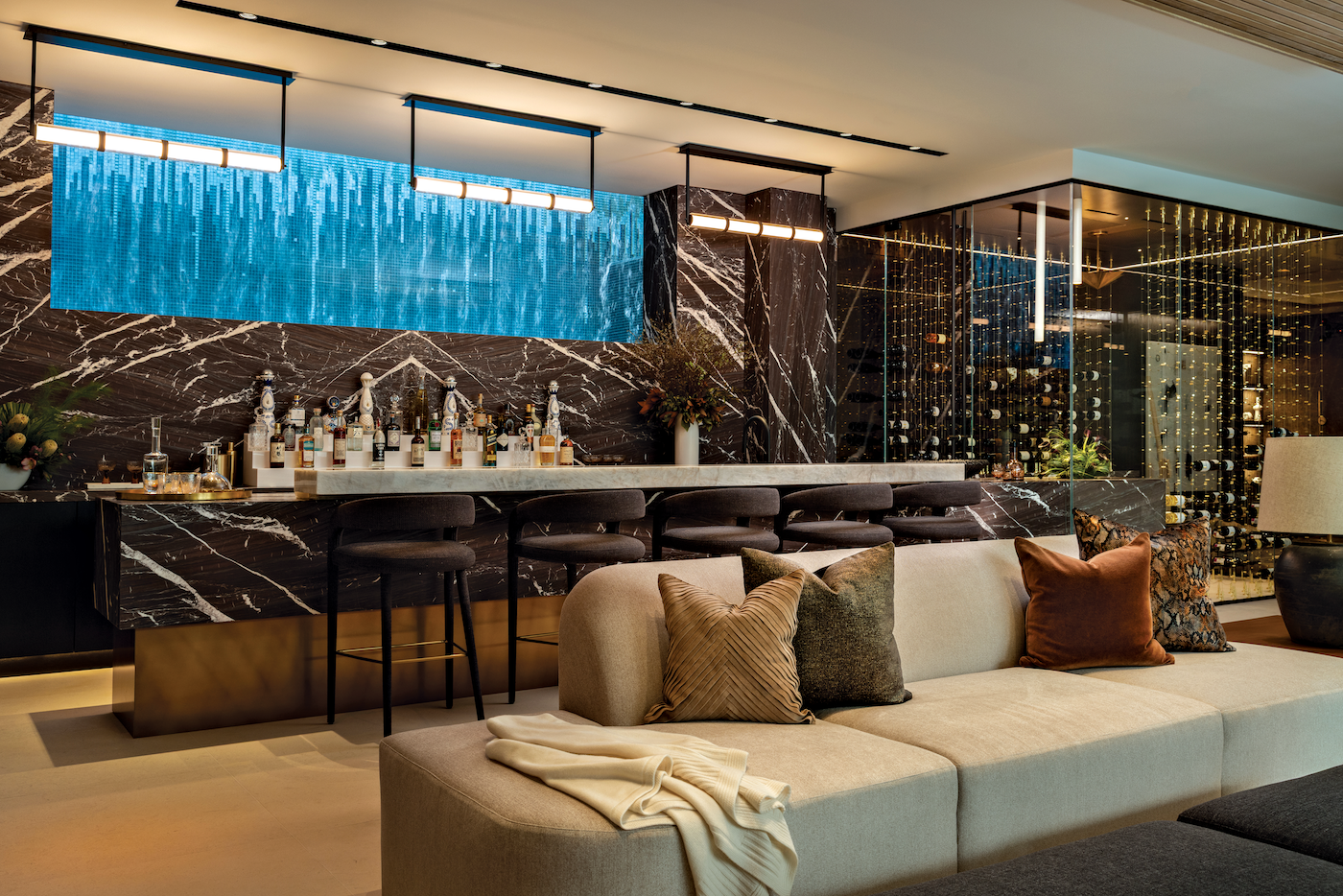 Lower-level bar wrapped in marble with dramatic glass feature revealing pool above.