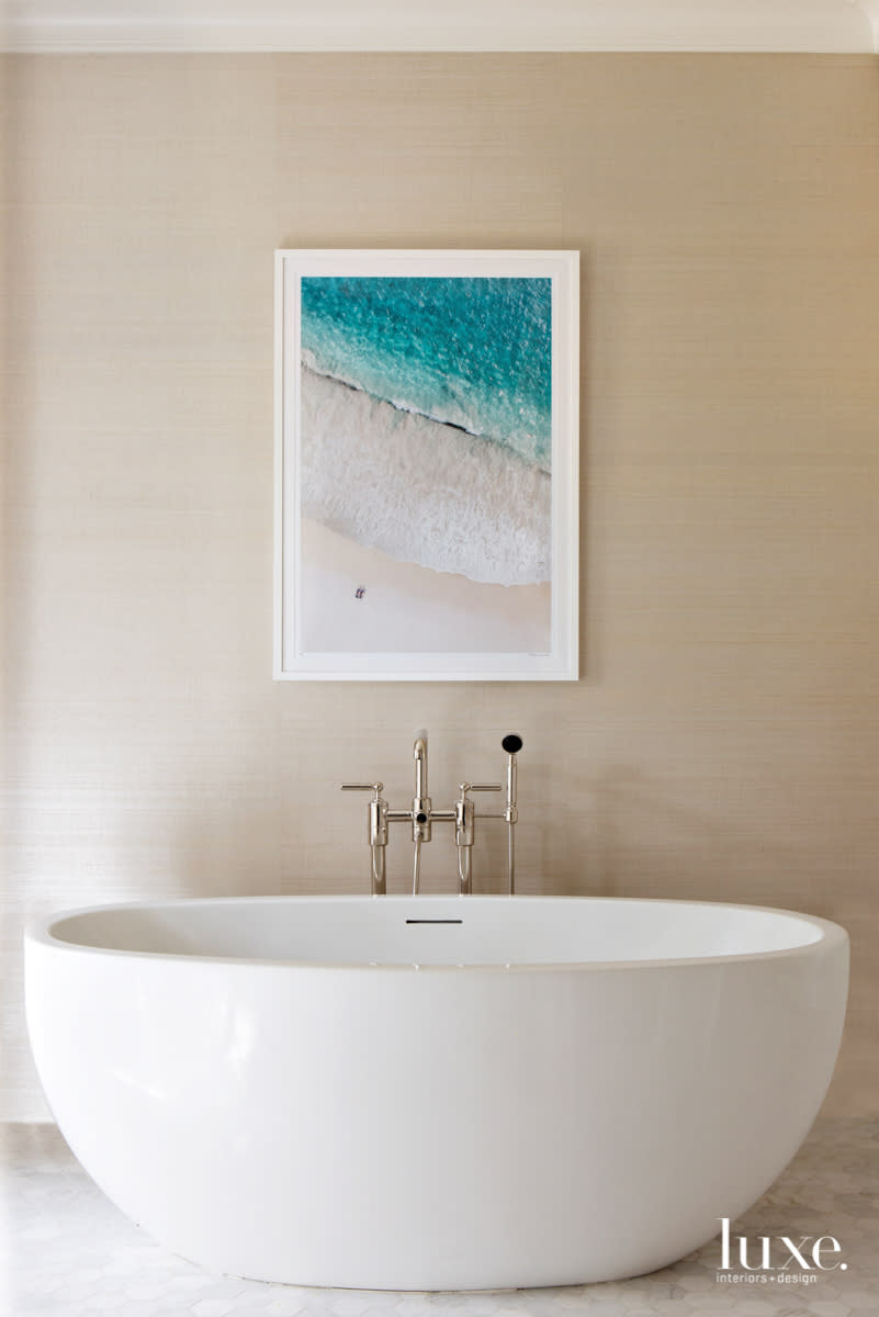 Serene master bathroom with freestanding tub and Gray Malin photography