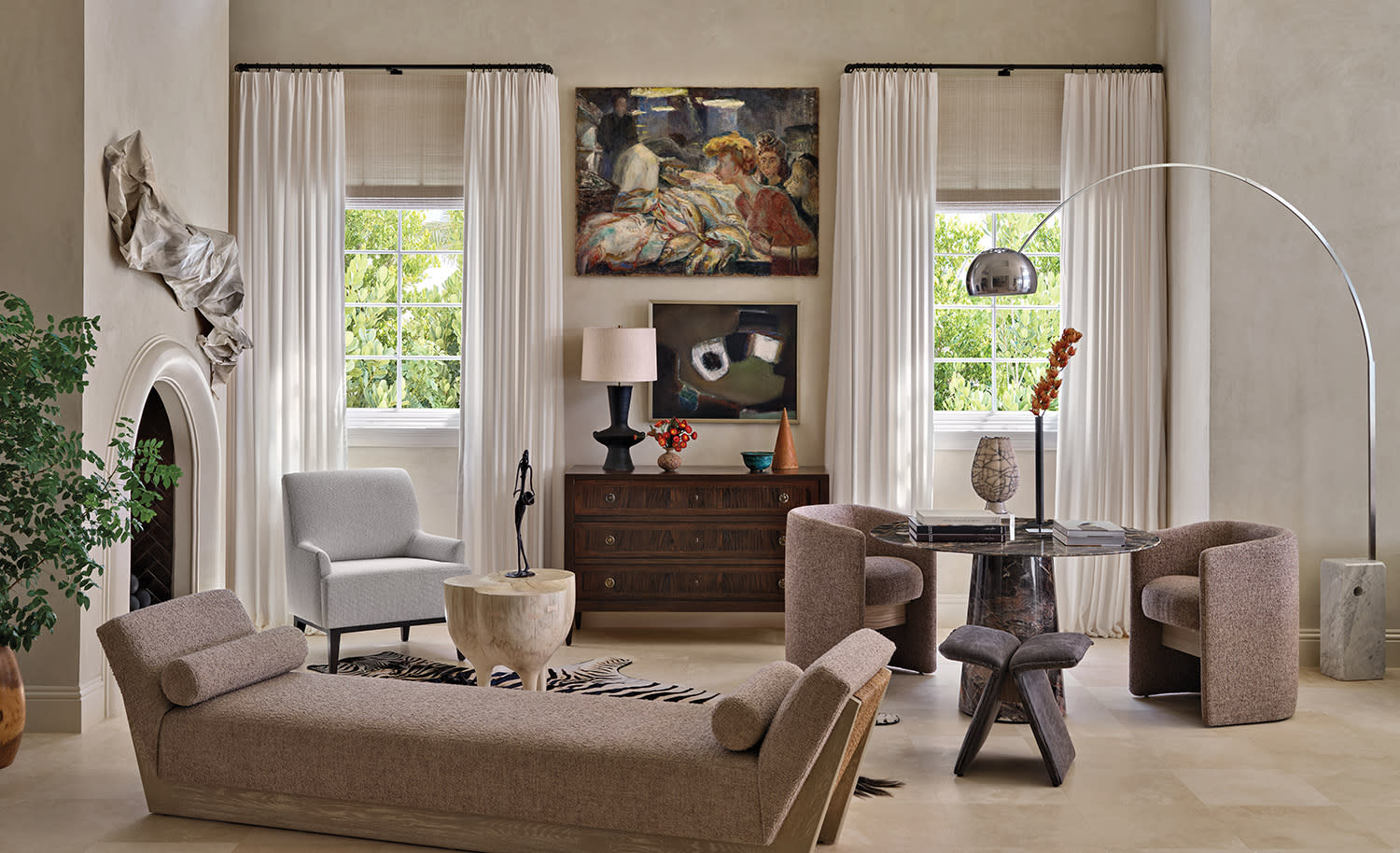 Stylish living room with neutral tones features a modern chaise, a round glass table and large windows