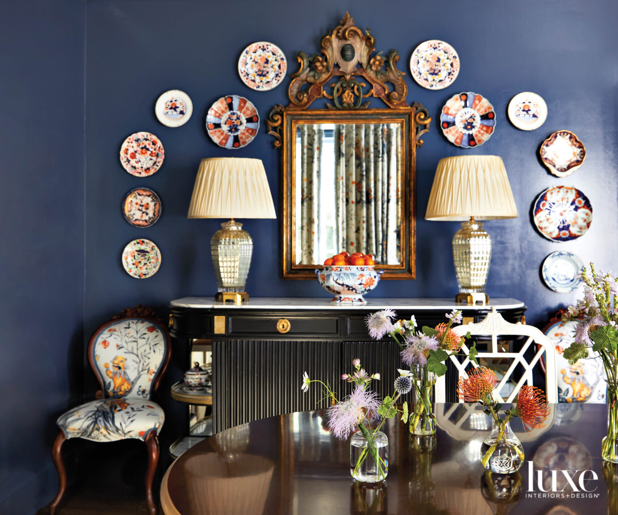 Dining sideboard against navy painted walls with mounted antique plates surrounding mirror