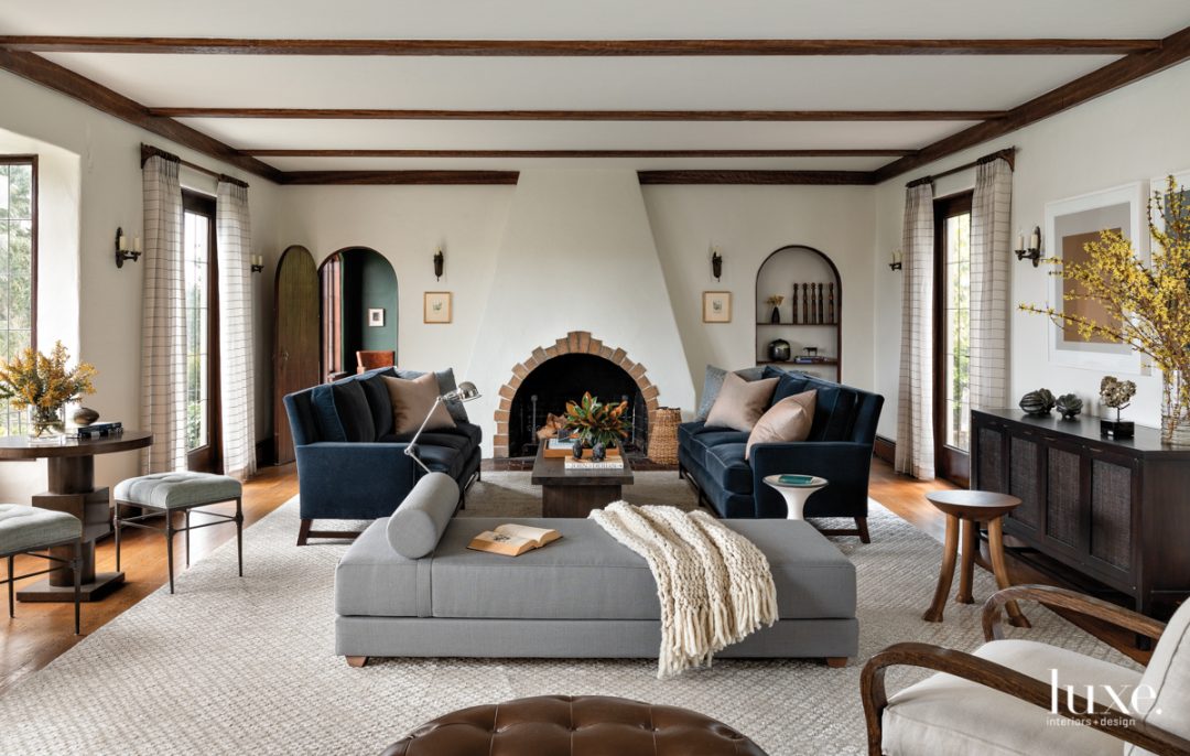 In the living room, the original fireplace and French doors remain. A CB2 daybed is centered on a rug from Driscoll Robbins Fine Carpets. Kravet sofas, upholstered in mohair from HBF Textiles, face the RH coffee table.