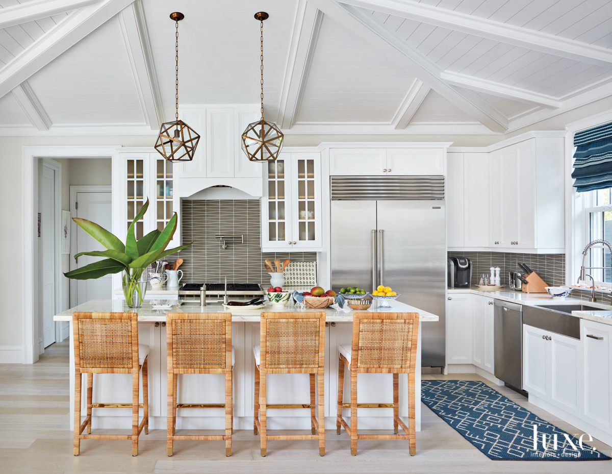 Serena &amp; Lily's Balboa counter stools are tucked under the kitchen island's Calacatta marble countertop. Vaughan's Fenton lanterns hang above, and Wolf appliances outfit the space.