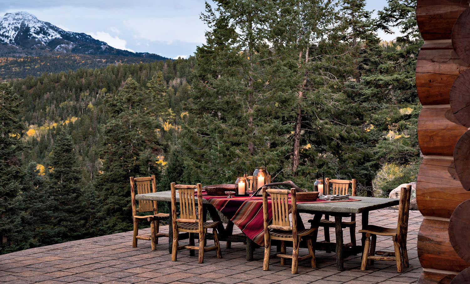 A terrace with a dining table decorated with a printed tablecloth and chairs overlooking the mountains