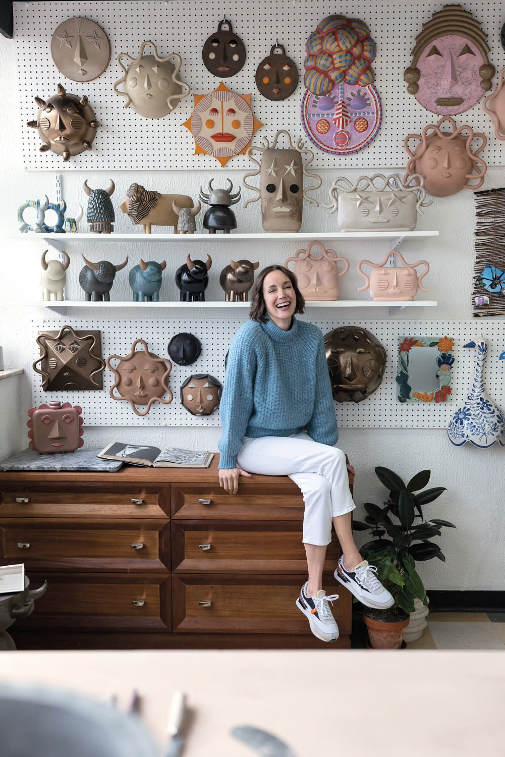 Smiling woman sitting on a chest of drawers