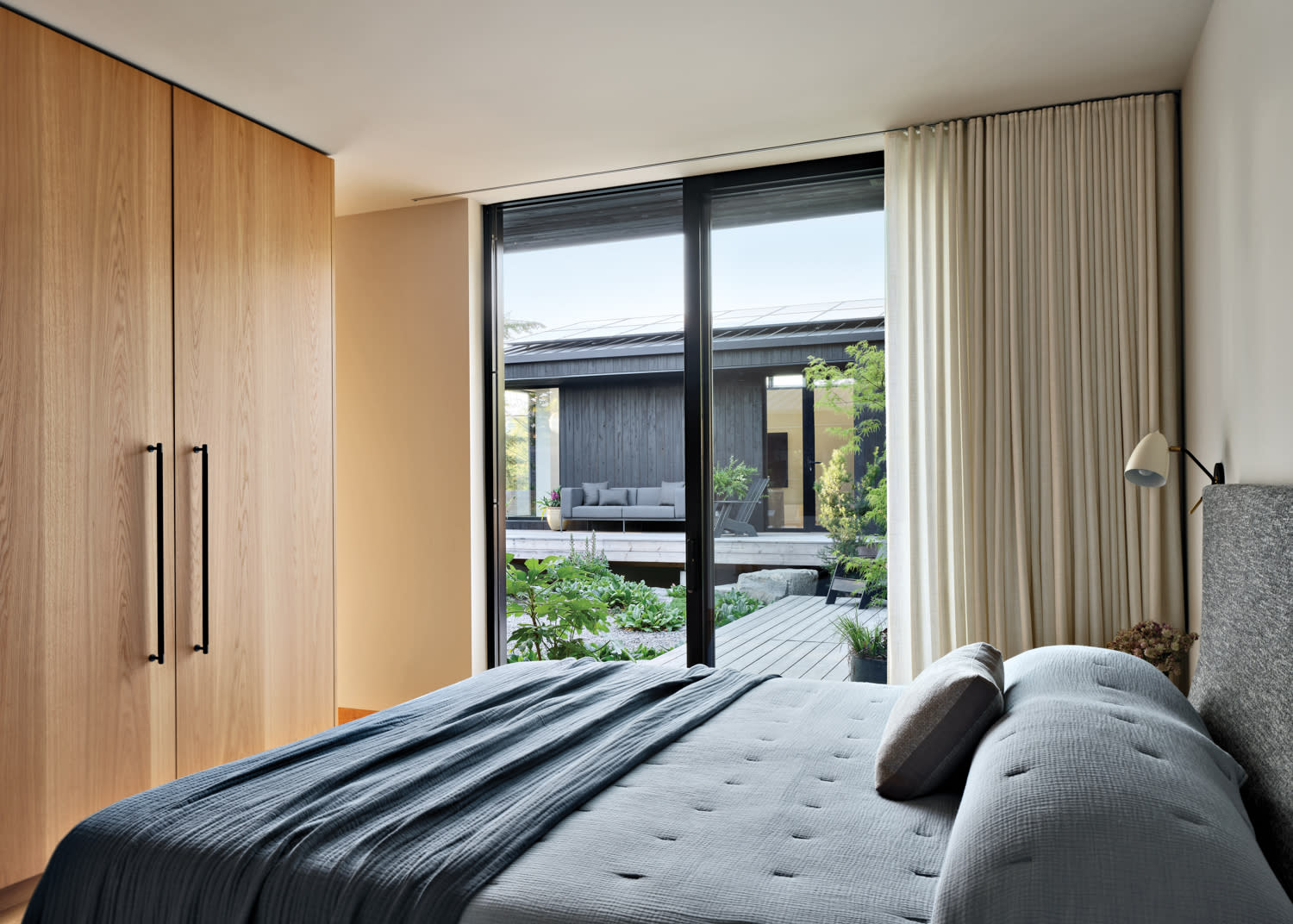 contemporary, minimalist bedroom with a light oak closet and gray bedding