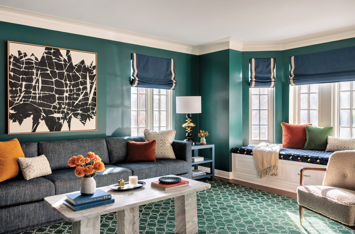 Living room with green walls, blue window treatments, green patterned carpeting, a couch, coffee table and window seat