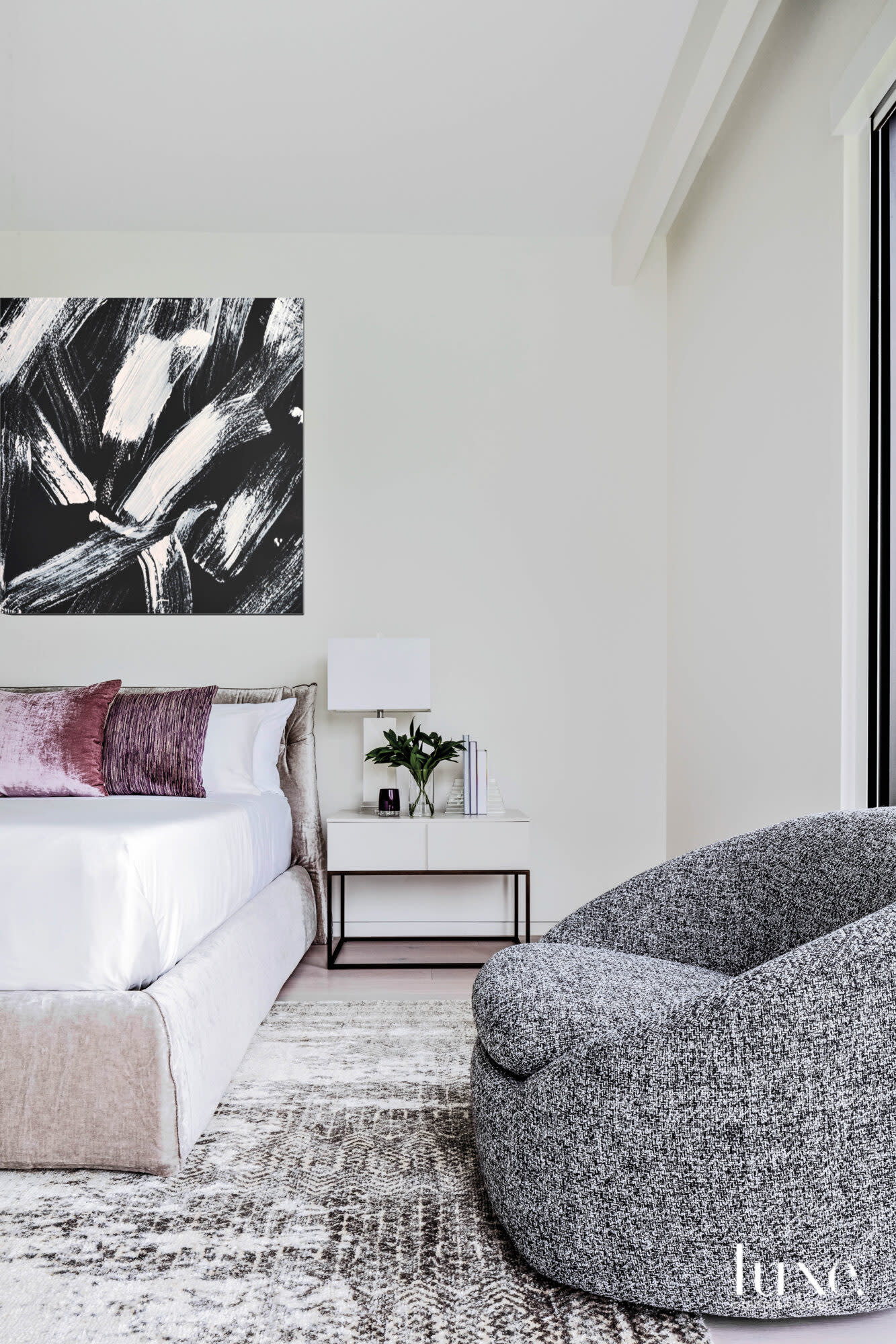 Master bedroom with a gray armchair and mauve pillows