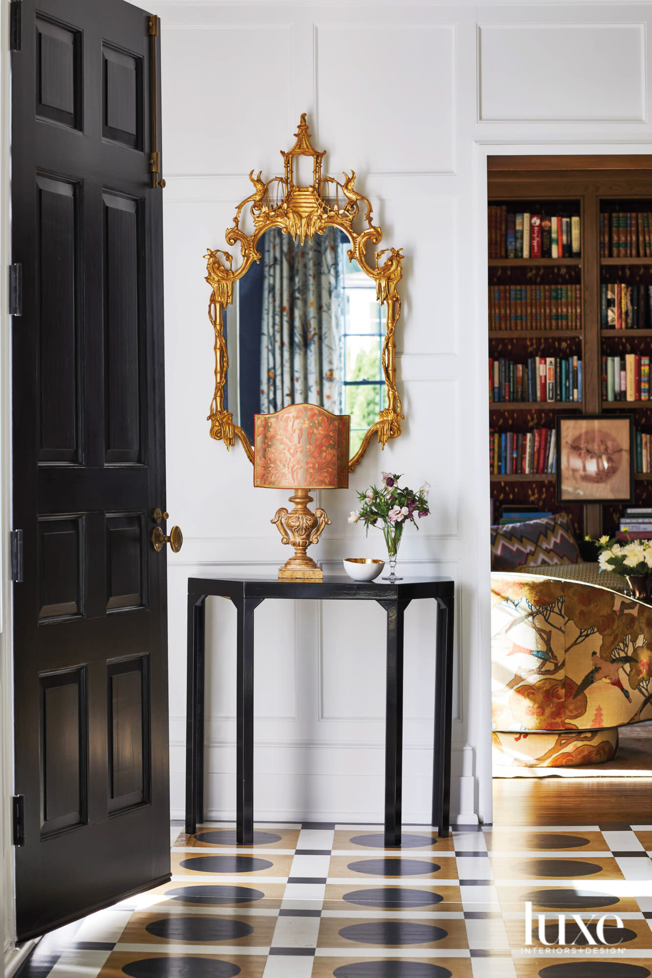 Entryway table with black door, gilt mirror and small, ornate lamp