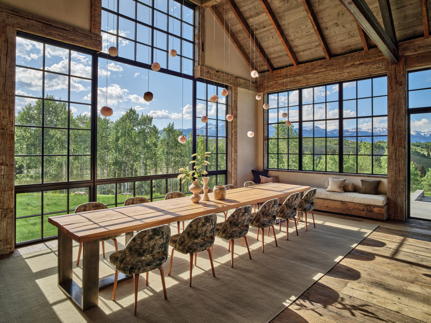 A spacious dining room featuring a large window and polished wooden floor, creating a warm and inviting atmosphere.