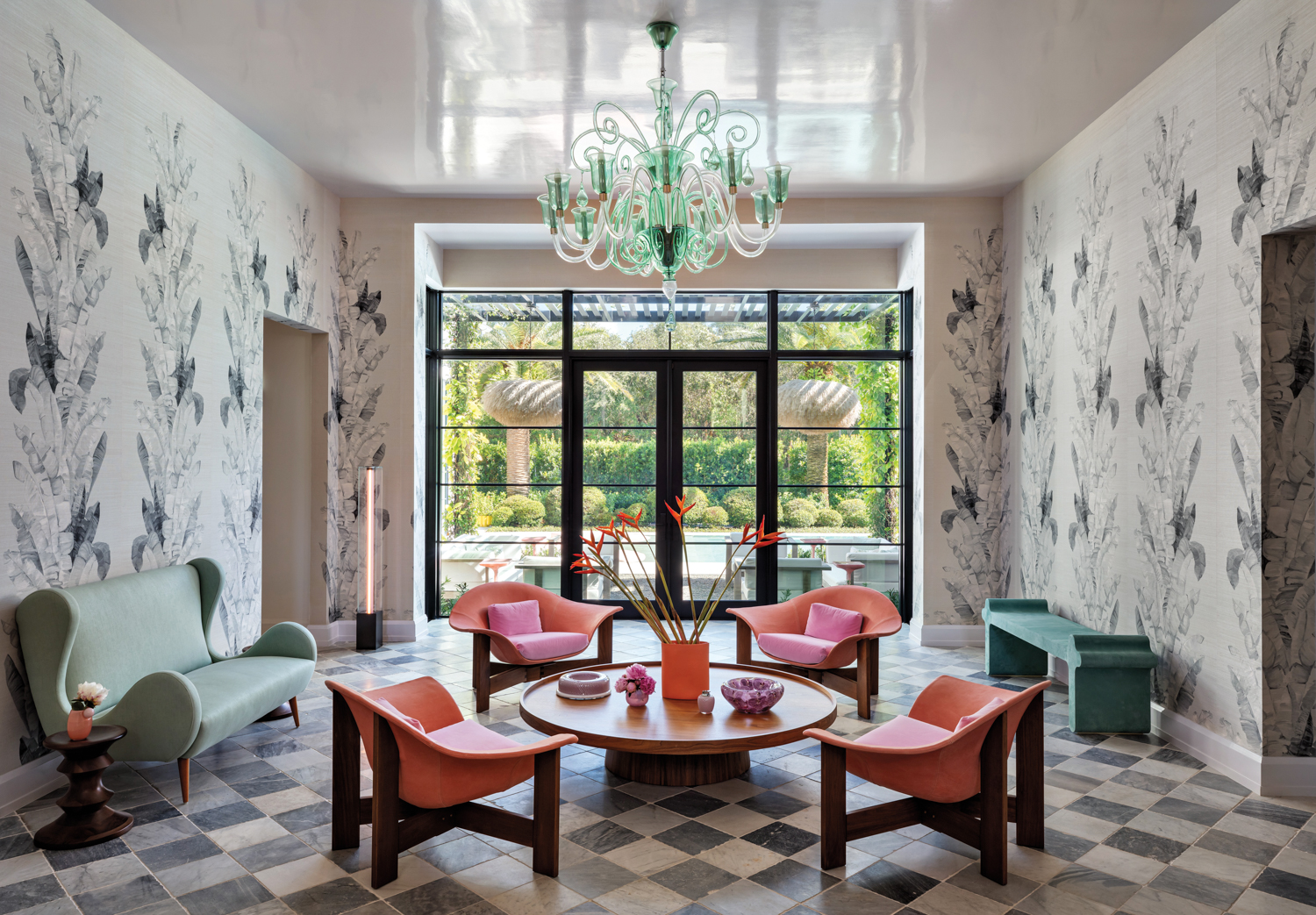 Gallery with murano glass chandelier, low pink chairs, round coffee table and checkerboard flooring