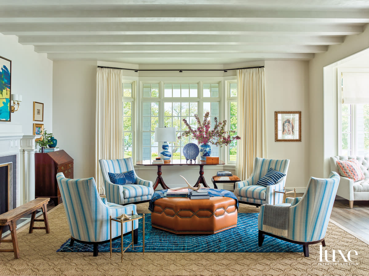 Blue-and-white striped chairs surrounding a leather ottoman.