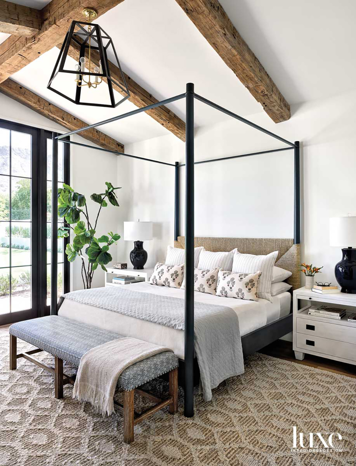 A fourposter bed in a zen bedroom with natural wood beams.