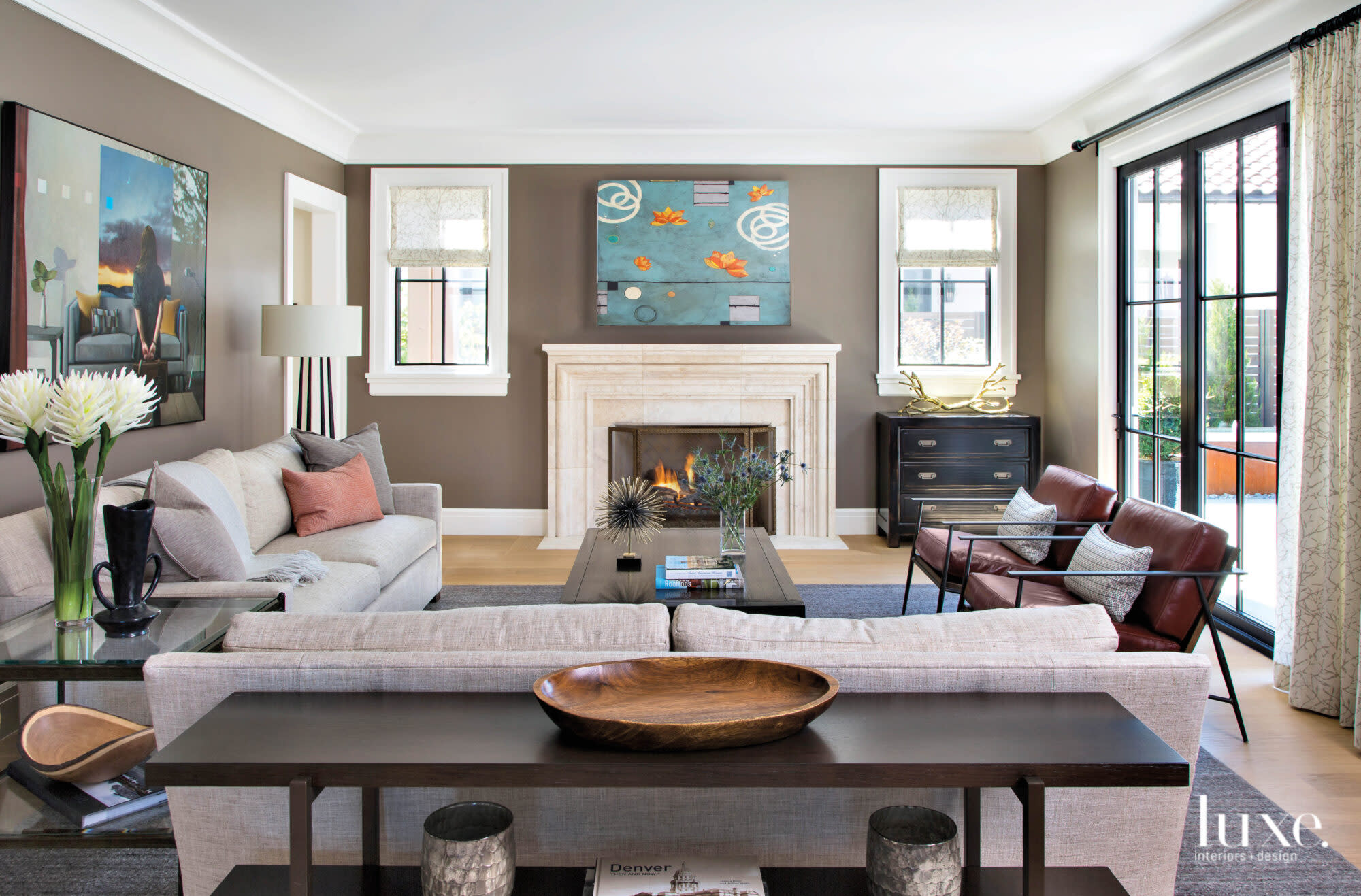 A living room has a white fireplace, olive walls light-colored furniture.