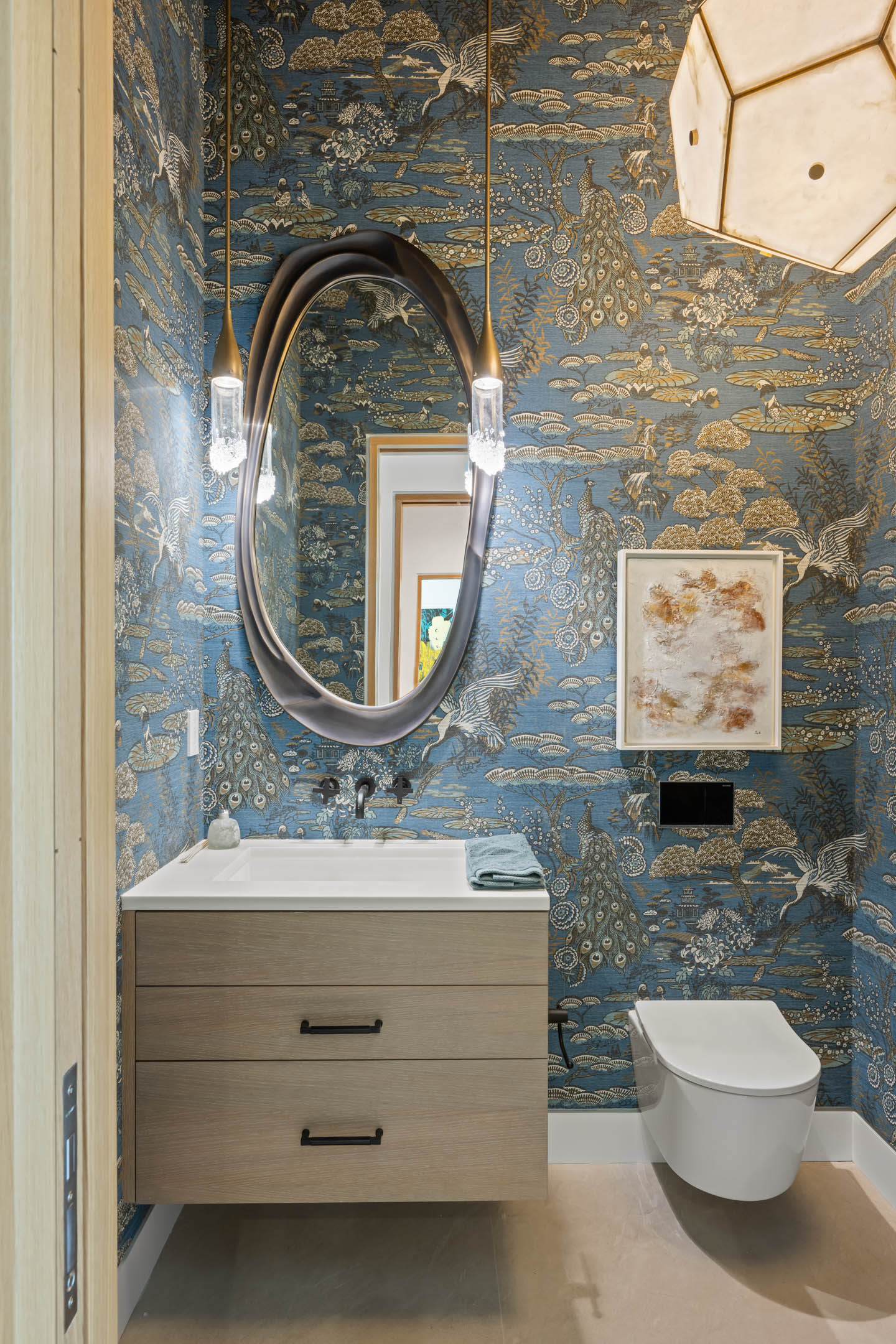 powder room with a nature-scene wallpaper and an oval silver-framed mirror