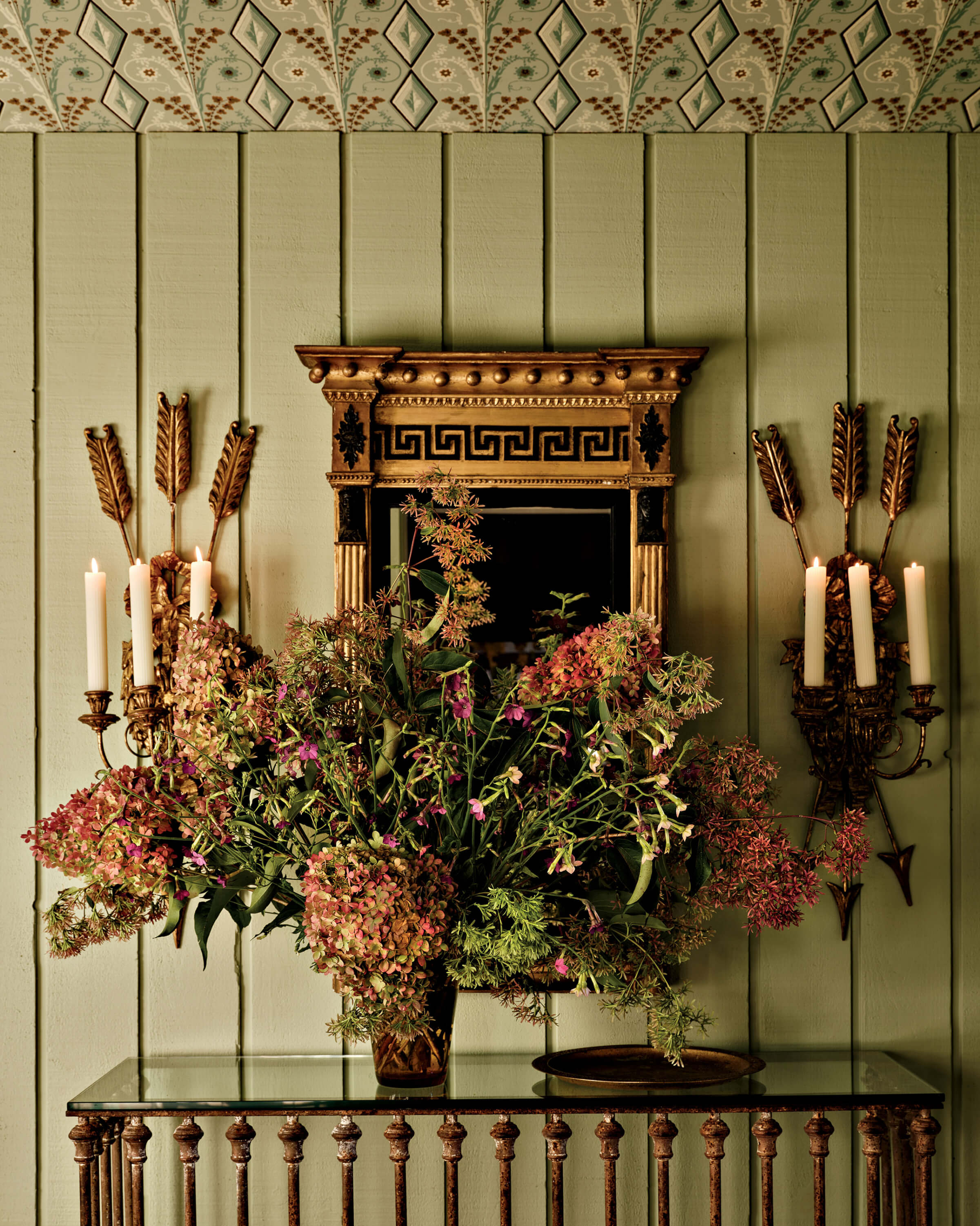 green wall with a Greek Revival mirror and bountiful blooms in a mud room