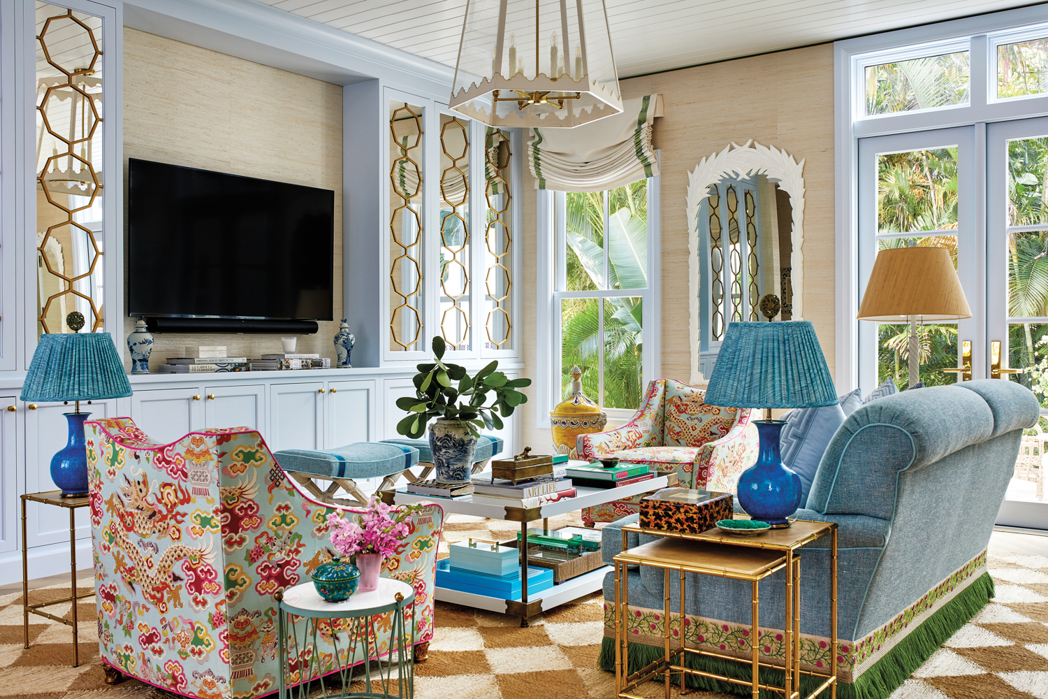 great room with patterned armchairs, blue sofa and white coffee table, a chandelier and wall mirror