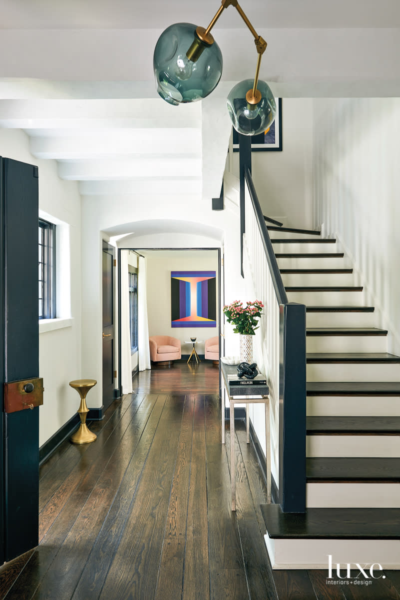 staircase with view of living room with pink armchairs and art