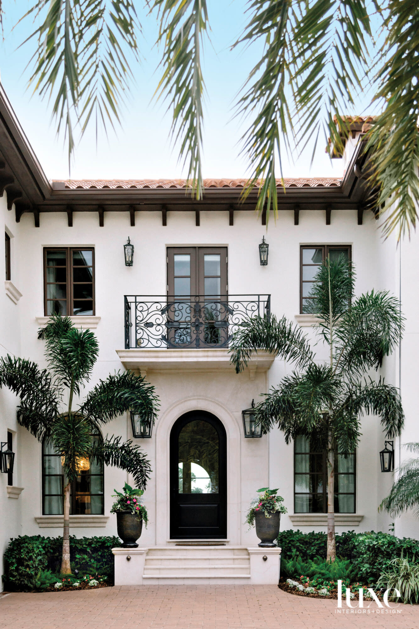 Mediterranean-style exterior of home with entrance framed by palms.