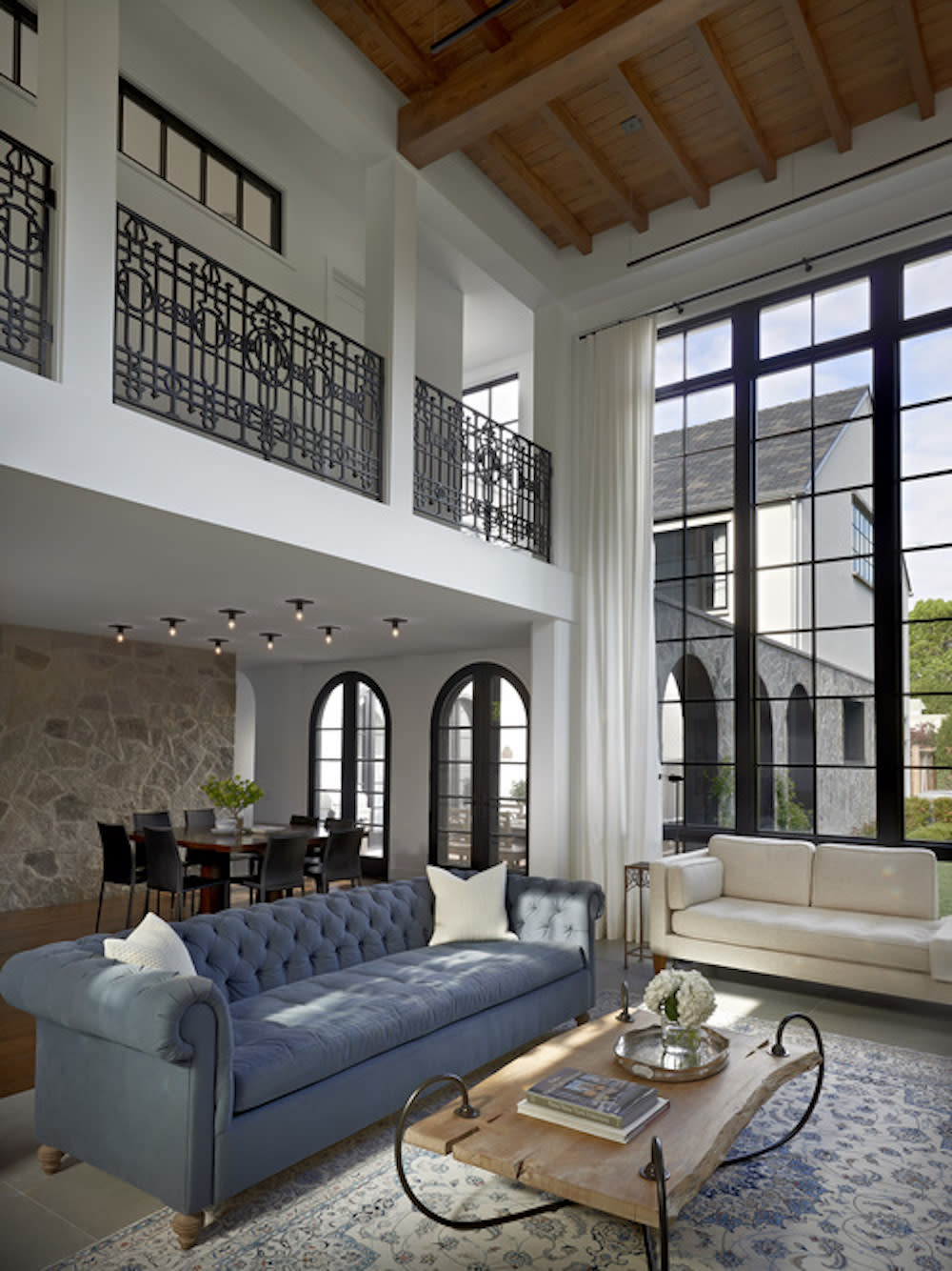 Living space with floor to ceiling window, wooden ceiling and decorative loft railing