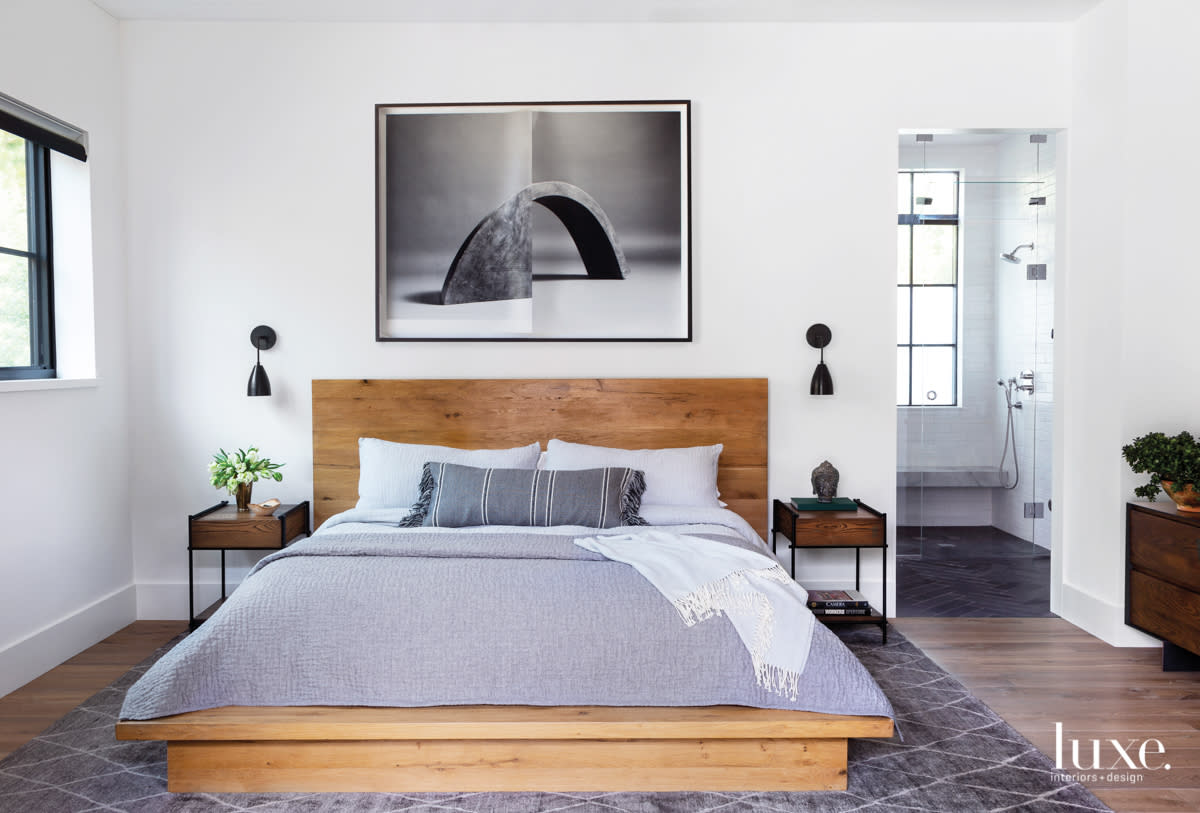 master bedroom with wood bed, wood side tables and art above the bed frame