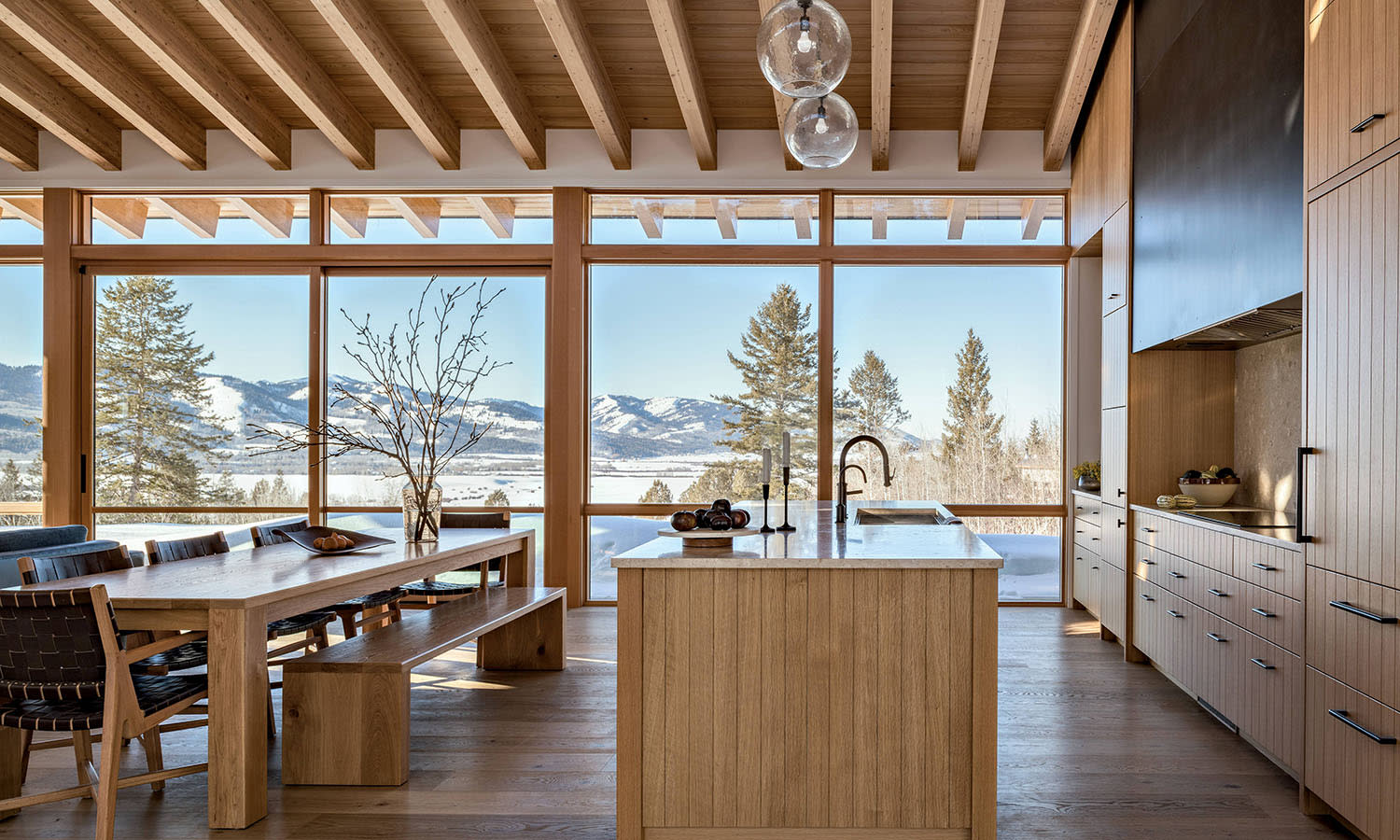 A kitchen with oak cabinetry, terrazzo countertops and backsplash and large glass windows.